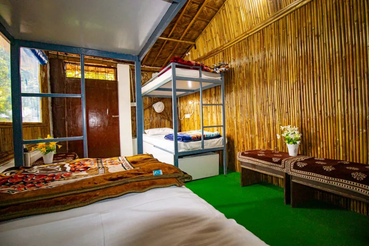Bamboo dormitory cottage interior with beds and seating for yoga students in Rishikesh