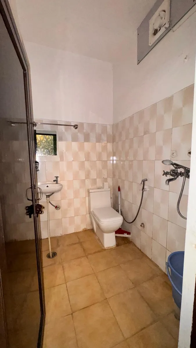Clean attached private bathroom with shower and Western toilet in yoga school accommodation