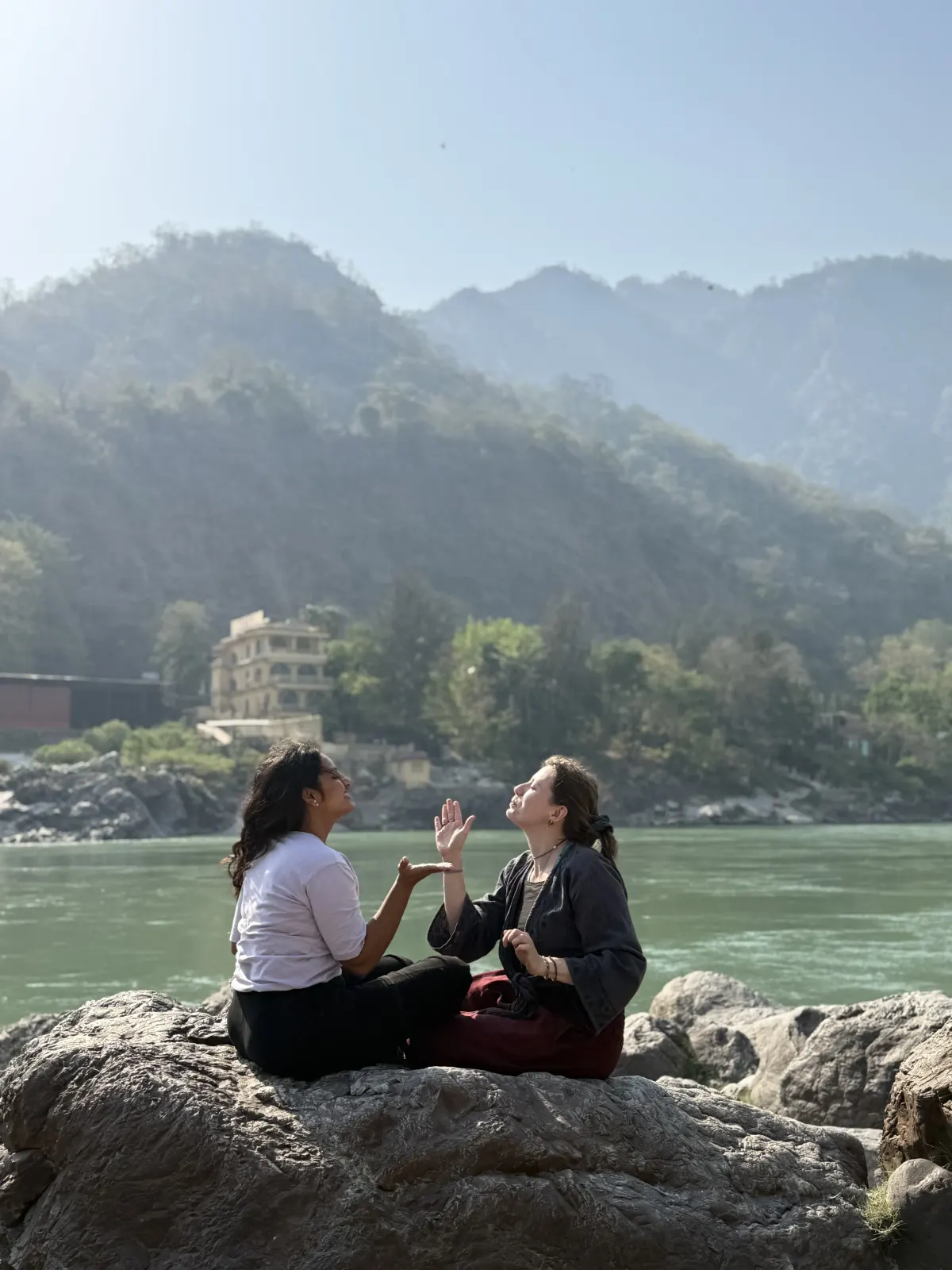 Students relaxing on rocks by the Ganga with the Rishikesh hills behind