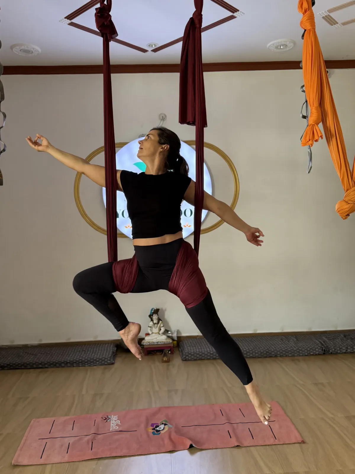 Student balancing in an aerial yoga hammock pose at Swaastik Yog School, Rishikesh