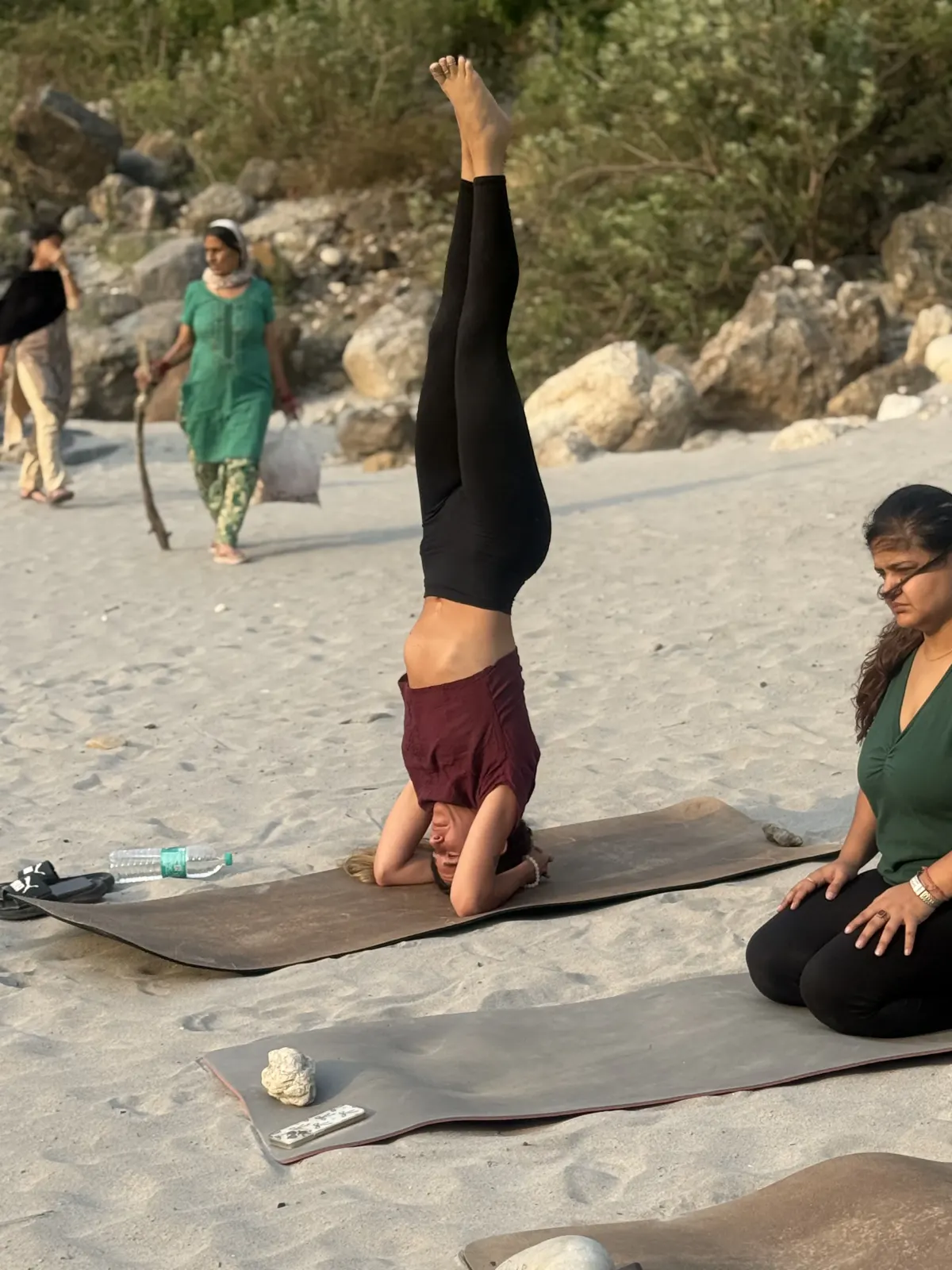 Student practising a supported headstand on the Ganga beach in Rishikesh